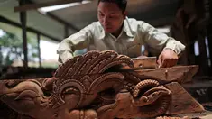 Seorang pengrajin kayu dari komunitas etnis Newar mengukir kayu di Lalitput, Nepal (19/7). Komunitas pengrajin kayu ini memperbaiki pintu dan jendela kayu yang rusak akibat gempa Nepal menjadi kayu ukiran yang menawan. (AP Photo/Niranjan Shrestha)