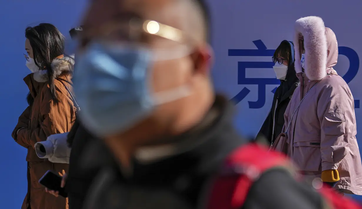 Orang-orang yang memakai masker untuk melindungi diri dari virus corona berjalan melalui distrik perbelanjaan Wangfujing di Beijing, Minggu (12/12/2021).  (AP Photo/Andy Wong)