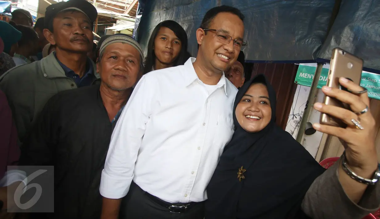 Calon Gubernur DKI Jakarta Anies Baswedan berfoto dengan warga saat mengunjungi Pasar Bambu Kuning, Sunter Agung, Jakarta Utara, Senin (31/10). Di pasar tradisional tersebut, Anies mendengarkan keluhan pedagang (Liputan6.com/Immanuel Antonius)