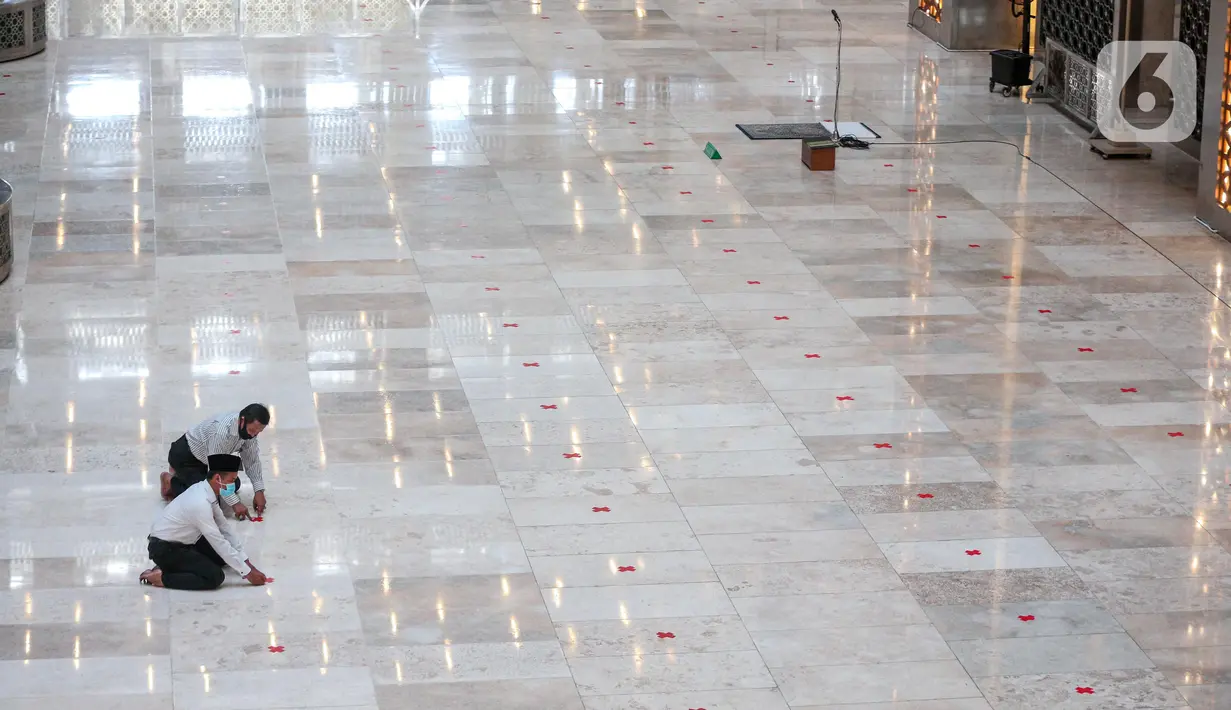 Petugas memasang tanda silang antar saf di Masjid Istiqlal, Jakarta Pusat, Selasa (2/6/2020). Masjid Istiqlal merupakan salah satu sarana ibadah yang dipersiapkan menerapkan prosedur standar new normal atau kenormalan baru. (Liputan6.com/Faizal Fanani)