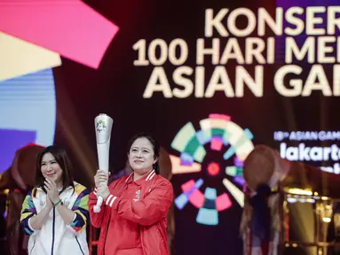 Menko PMK Puan Maharani disaksikan Susi Susanti memegang obor untuk Asian Games 2018 saat peluncuran Torch Asian Games dalam konser 100 Hari Menuju Asian Games 2018 di Studio 6 Emtek, Jakarta, Kamis (10/5). (Liputan6.com/Faizal Fanani)