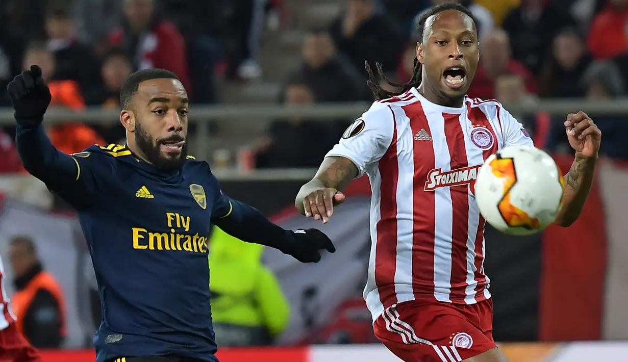 Striker Arsenal, Alexandre Lacazette (kiri) berebut bola dengan bek Olympiakos Piraeus, Ruben Semedo pada leg pertama babak 32 besar Liga Europa di Georgios Karaiskakis Stadium, Kamis (20/2/2020). Arsenal susah payah menaklukkan Olympiakos Piraeus 1-0. (ARIS MESSINIS / AFP)