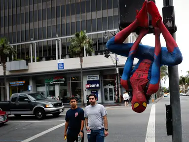 Rashad Rouse mengenakan kostum Spider-Man sembari bergelantungan di tiang lalu lintas untuk menarik perhatian turis di Hollywood Boulevard, Los Angeles, 25 Mei 2017. Pria 27 tahun itu bermimpi namanya akan masuk di Hollywood Walk of Fame (AP/Jae C. Hong)