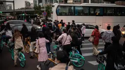 Orang-orang mencoba melewati lalu lintas saat mereka bepergian dengan sepeda selama jam sibuk di Beijing, China pada 14 Oktober 2020. (Photo by NICOLAS ASFOURI / AFP)