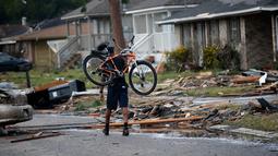 Seorang pria membawa sepedanya berjalan diantara puing-puing rumah yang rusak akibat Tornado di New Orleans, AS (7/2). Selain merusak bangunan dan rumah, sediktnya 25 orang luka-luka akibat hantaman tornado tersebut. (AP Photo/Gerald Herbert)