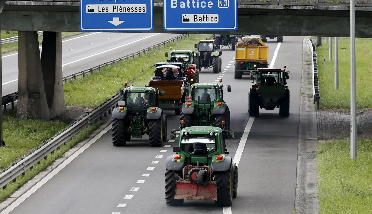 Peternak sapi perah menaiki traktor mereka di jalan tol atau jalan bebas hambatan saat melakukan aksi protes di Battice, Belgia, Kamis (30/7/2015). Aksi protes tersebut berkaitan dengan rendahnya harga jual susu. (REUTERS/Francois Lenoir)