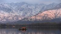 Orang-orang menikmati perjalanan dengan perahu dengan latar belakang pegunungan yang tertutup salju di danau Dal di Srinagar (11/1/2022). Danau Dal yang merupakan danau terbesar kedua di propinsi Jammu dan Kashmir negara bagian India ini merupakan pusat pariwisata dan rekreasi. (AFP/Tauseef Mustafa)