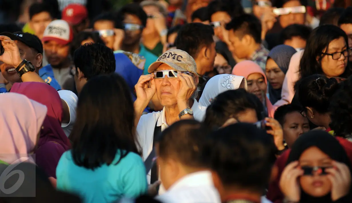 Warga menggunakan kacamata khusus untuk melihat proses gerhana matahari di sekitar Taman Ismail Marzuki, Jakarta, Rabu (9/3/2016). Di Jakarta, fenomena gerhana matahari 90% bisa diamati selama 2,11 menit. (Liputan6.com/Helmi Fithriansyah)   