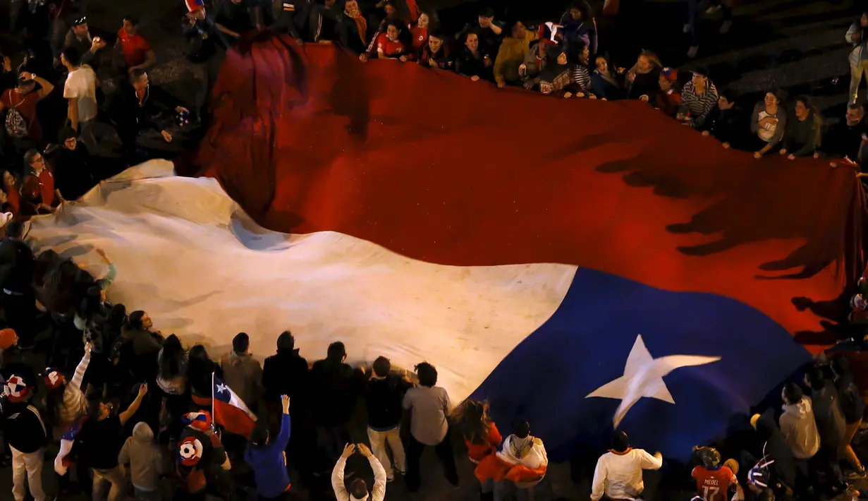 Sejumlah suporter Chili mengibarkan bendera nasional Chili merayakan kemenangan Chili atas Argentina di final Copa Amerika 2015 di Santiago, (4/7/2015). Chili menang lewat adu penalti atas Argentina dengan skor 4-1. (REUTERS/Carlos Garcia Rawlins)
