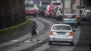 Seorang wanita berjalan di jalan yang tertutup abu dari gunung berapi di Pulau Canary La Palma, di Los Llanos de Aridane, Spanyol (1/10/2021). Retakan baru ini adalah yang ketiga yang retak terbuka sejak kawah Cumbre Vieja meletus di pulau La Palma 19 September. (AP Photo/Saul Santos)