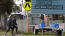 Orang-orang berjalan melewati tanda jam malam saat kota itu mengalami penguncian keenam saat memerangi wabah varian Delta dari coronavirus.di Melbourne (25/8/2021). (AFP/William West)