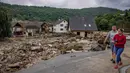 Sepasang suami istri berjalan melewati rumah-rumah yang hancur di Schuld, Jerman, Kamis (15/7/2021). Korban banjir di Jerman barat bertambah menjadi setidaknya 58 orang per Kamis malam (15/7) waktu setempat.(AP Photo/Michael Probst)