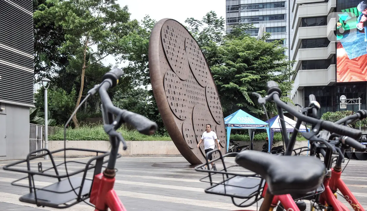 Pejalan kaki melintas dekat Tugu Sepeda di Jalan Jenderal Sudirman, Jakarta Pusat, Minggu (23/10/2022). Tugu tersebut dibangun dengan biaya senilai Rp 800 juta. (merdeka.com/Iqbal S. Nugroho)