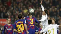 Bek Barcelona, Gerard Pique, duel udara dengan bek Real Madrid, Raphael Varane, pada laga La Liga 2019 di Stadion Camp Nou, Rabu (18/12). Kedua tim bermain imbang 0-0. (AP/Bernat Armangue)