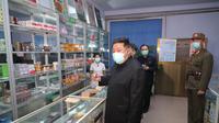 Pemimpin Korea Utara Kim Jong Un mengenakan masker memeriksa apotek di tengah wabah Covid-19 di Pyongyang, Korea Utara pada 15 Mei 2022. Korea Utara telah memobilisasi militernya untuk mendistribusikan obat-obatan COVID dan mengerahkan lebih dari 10.000 petugas kesehatan untuk membantu melacak pasien potensial terkena Covid-19. (STR/KCNA VIA KNS/AFP)