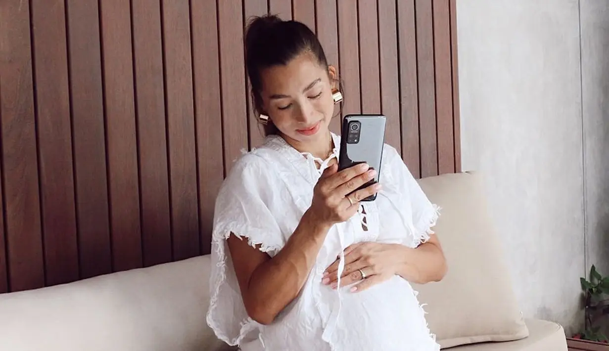 Kesan modern tercipta dari boxy dress bernuansa putih dipadukan dengan aksesori emas. Tentunya gaya ini bisa dipakai oleh siapapun, segala usia. (Foto: Jennifer Bachdim/ Instagram)