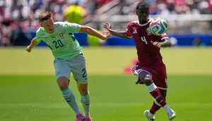Pemain Swiss, Michel Aebischer (kiri), berebut bola dengan pemain Qatar, Issa Laye, dalam pertandingan Grup B Piala Dunia 2026, Minggu (14/6/2026). (AP Photo/Eugene Hoshiko)