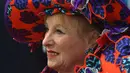 Wanita paruh baya memakai hiasan kepala lengkap dengan bajunya yang bercorak bunga saat menghadiri balap kuda Melbourne di arena pacuan kuda Flemington Racecourse di Melbourne, Australia (1/11). (AFP/Paul Crock)