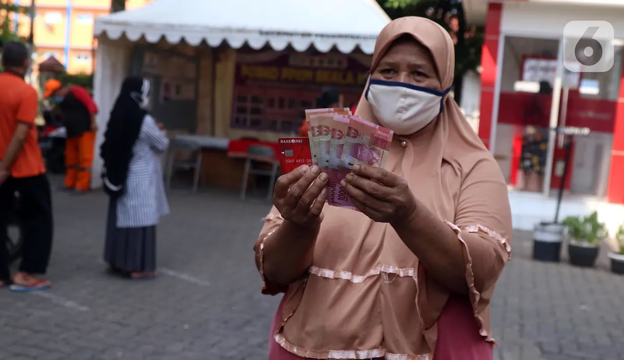 Warga menunjukkan uang usai melakukan penarikan bantuan sosial tunai (BST) di ATM Bank DKI di Jakarta, Selasa (20/7/2021). Pemprov DKI Jakarta resmi mencairkan BST kepada warga DKI Jakarta. (Liputan6.com/Angga Yuniar)