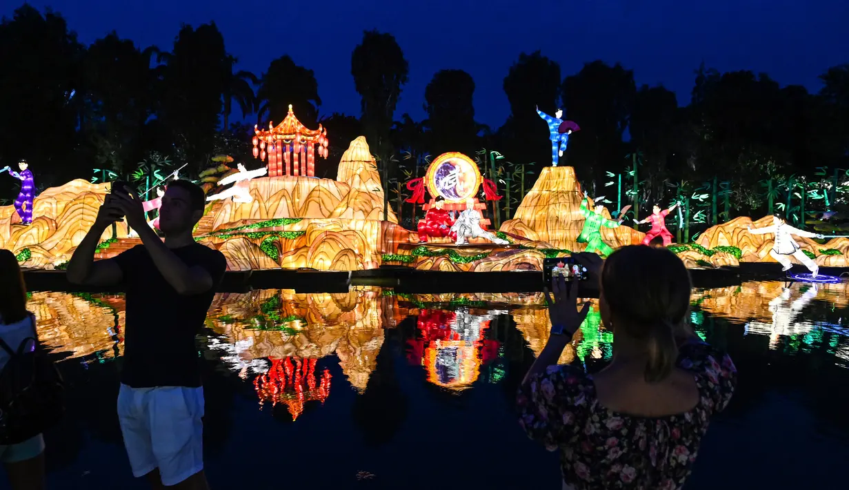Pengunjung mengambil gambardengan latar belakang lentera untuk Mid-Autumn Festival di Gardens by the Bay, Singapura, Selasa (27/8/2019). Festival ini sebagai penanda berakhirnya panen musim gugur atau Mid-Autumn sekaligus merupakan momen untuk memanjatkan syukur kepada dewa-dewi. (Roslan RAHMAN/AFP)
