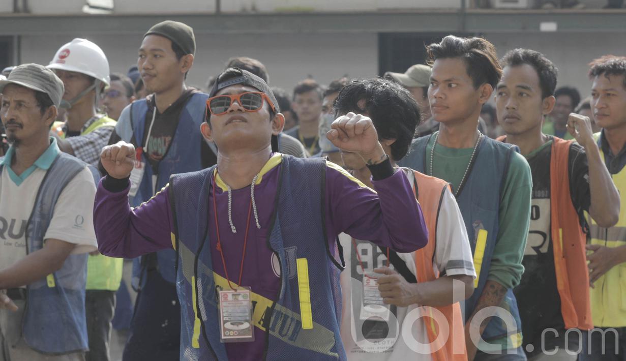 Seorang pekerja menikmati senam sebelum bekerja di proyek renovasi Stadion Utama Gelora Bung Karno (SUGBK), Senayan. Senam tersebut untuk meningkatkan kebugaran dan semangat pekerja. (Bola.com/M Iqbal Ichsan)