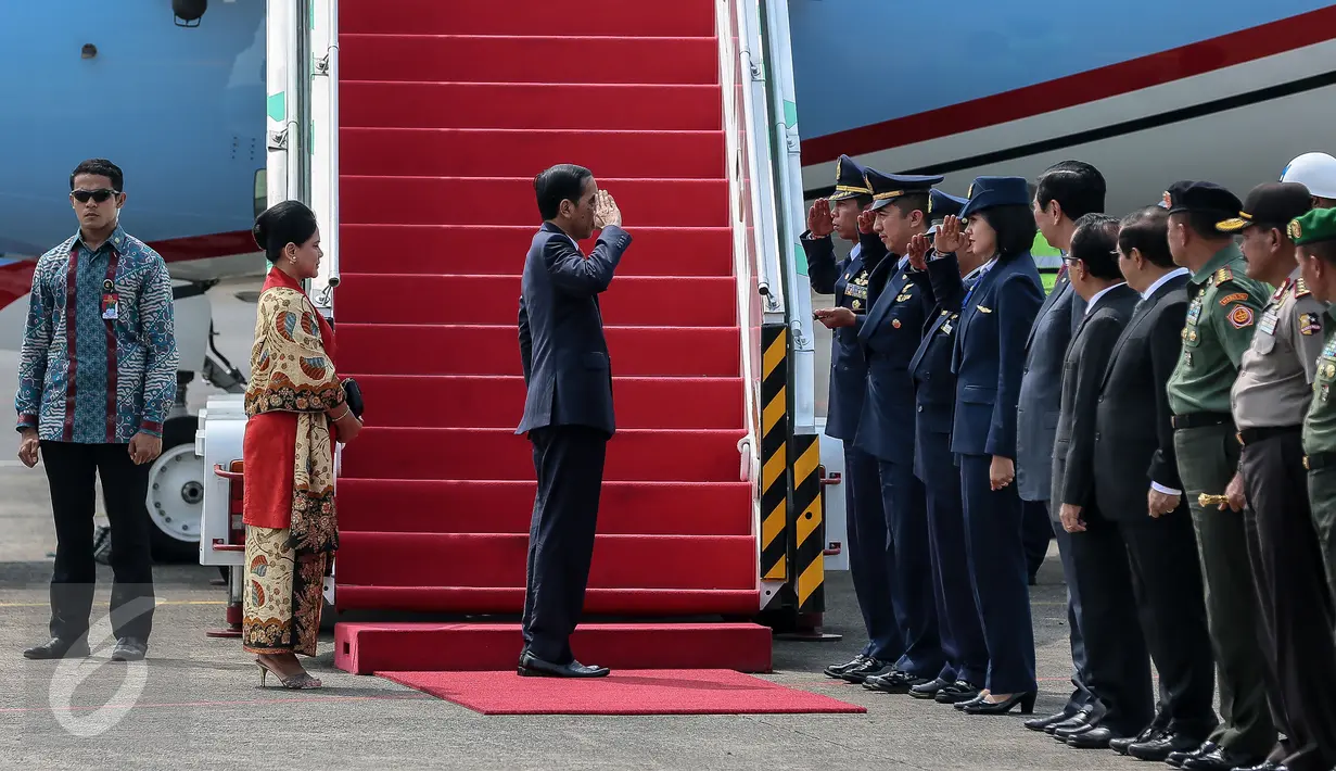 Presiden Jokowi didampingi Ibu Negara Iriana memberi hormat kepada kru pesawat Kepresidenan setibanya dari Paris di Bandara Halim Perdanakusuma, Jakarta Timur, Rabu (2/12) pagi. (Liputan6.com/Faizal Fanani)