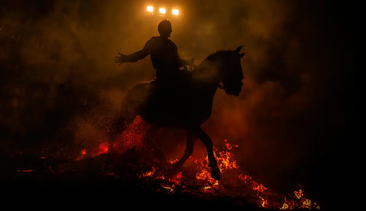 Seorang pria menunggang kuda melintasi kobaran api dalam tradisi tahunan Luminarias memperingati Hari Santo Anthony (santo pelindung hewan) di San Bartolome de Pinares, Spanyol, 16 Januari 2023. Tradisi yang sudah berlangsung selama 500 tahun ini dilakukan sebagai upaya 'pemurnian' hewan dengan cara melintasi kobaran api. (AP Photo/Manu Fernandez)