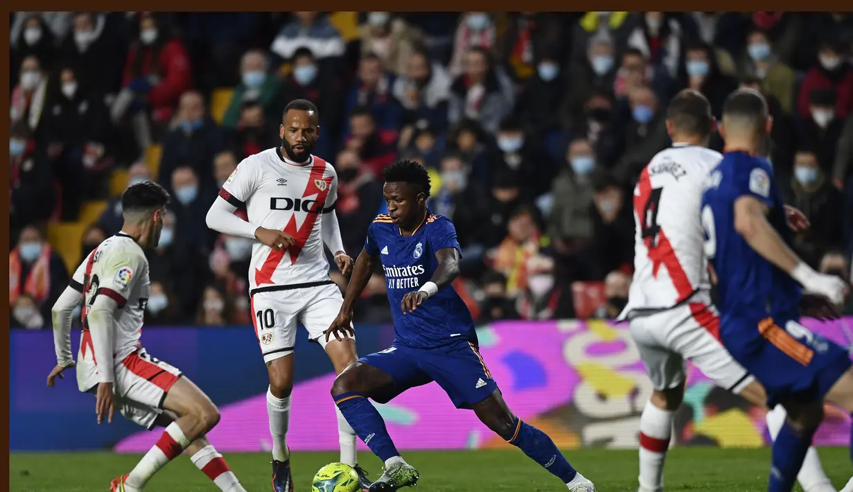 Penyerang Real Madrid, Vinicius Junior (tengah) mencoba menerobos pertahanan Rayo Vallecano pada pertandingan La Liga Spanyol di stadion Vallecas di Madrid, Spanyol, Minggu (27/2/2022). Real Madrid menang tipis atas Rayo Vallecano 1-0. (AP Photo/Jose Breton)