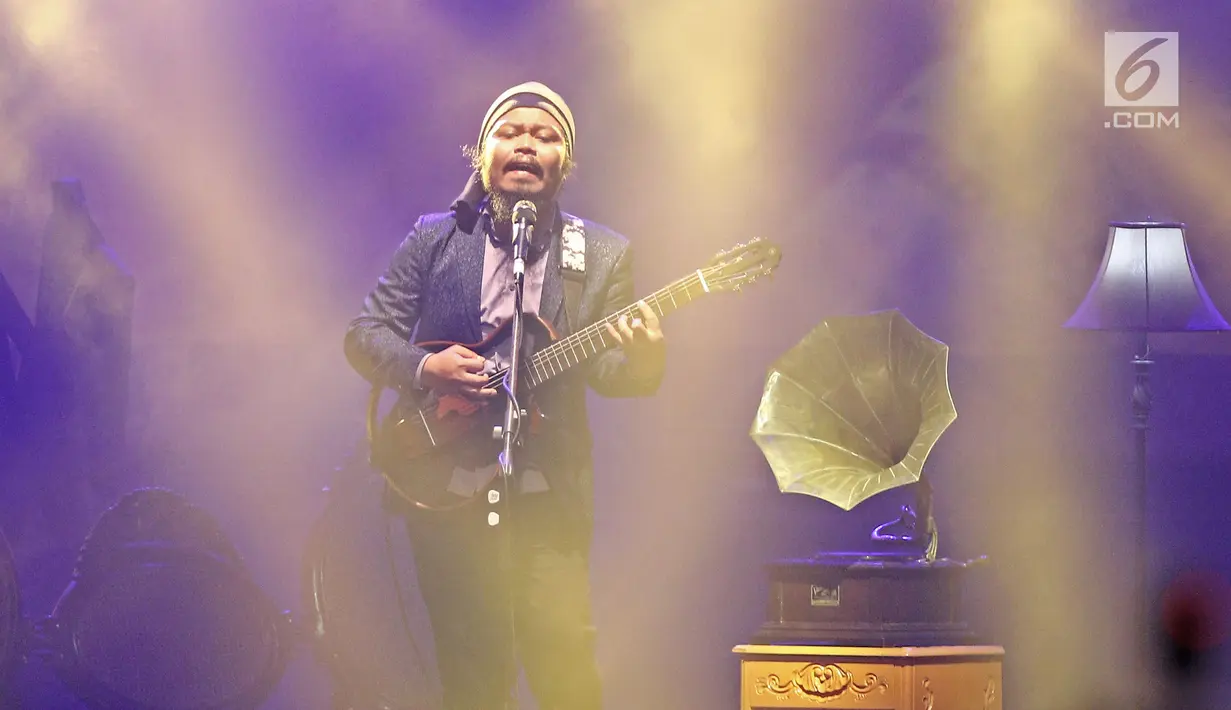 Vokalis band Payung Teduh, Is bernyanyi saat menghibur penonton dalam konser BBM x Liztomania vol.3 di Gedung Kesenian Jakarta, Selasa (14/11). (Liputan6.com/Herman Zakharia)