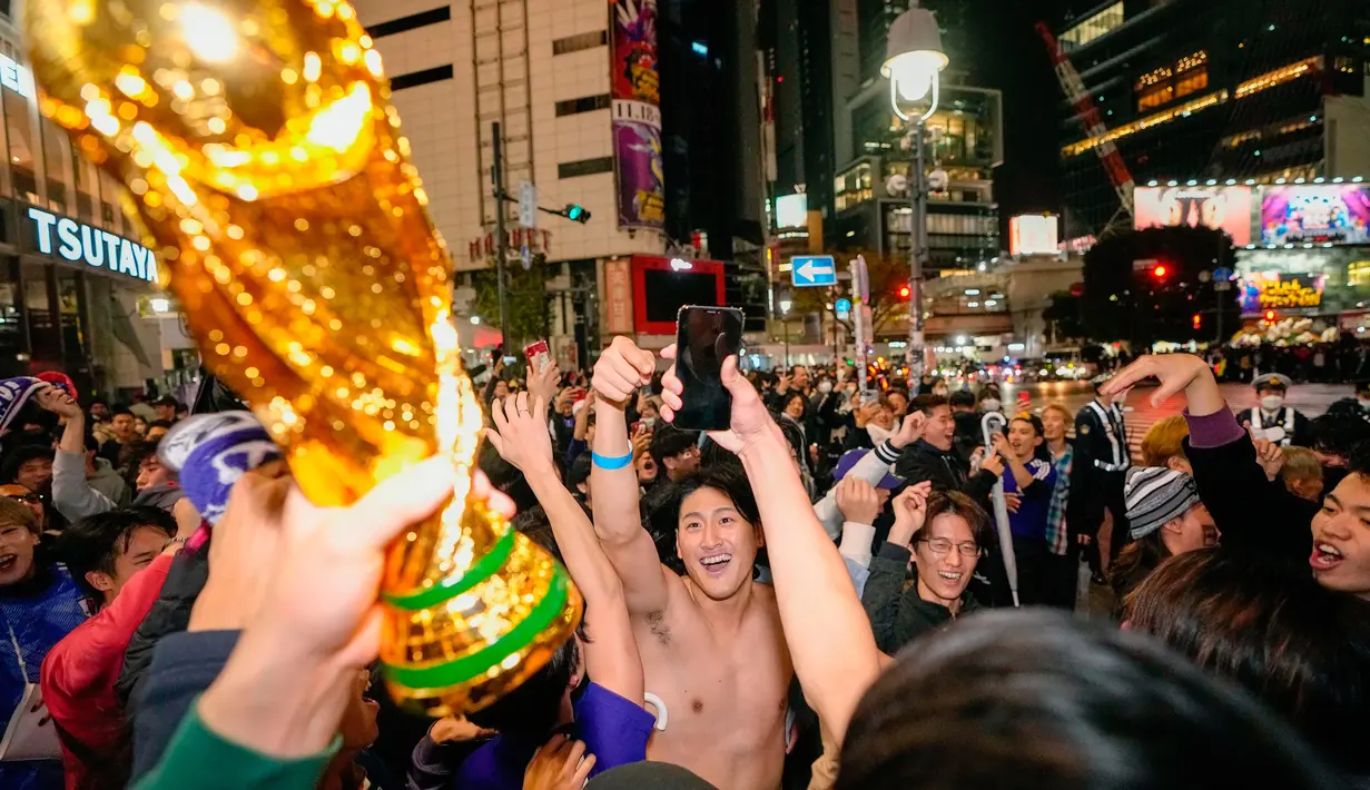 Orang-orang merayakan kemenangan timnas Jepang saat melawan Jerman di Piala Dunia Qatar 2022 di persimpangan Shibuya, Tokyo, Jepang, Kamis (24/11/2022). Timnas Jepang berhasil mencetak sejarah usai mengalahkan Jerman dalam laga Grup E. (Kyodo News via AP)