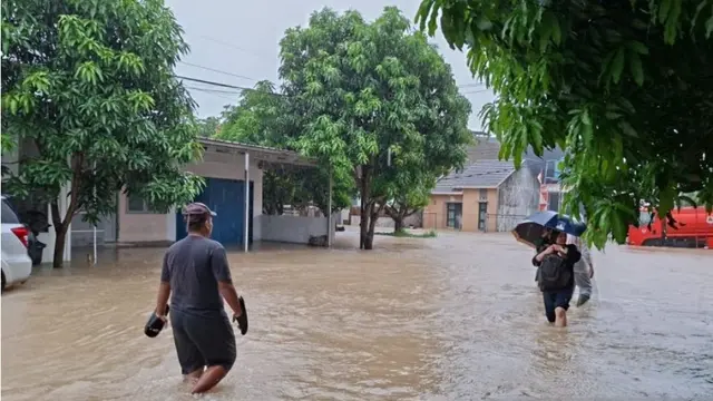 Warga melintas ditengah banjir di Kota Serang, Banten, Selasa (13/1/2026).