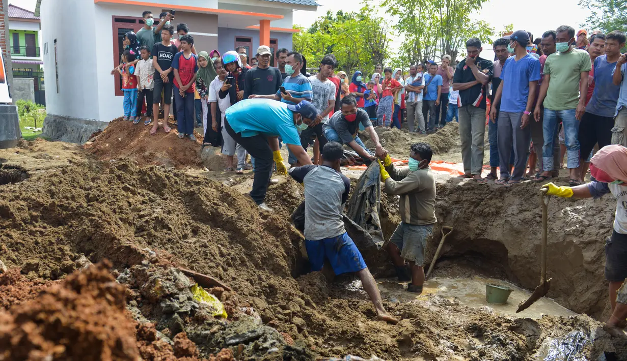 Warga membawa sisa-sisa korban tsunami dan gempa 2004 yang ditemukan di Kajhu, Provinsi Aceh (19/12). Penemuan korban tersebut membuat warga sekitar kaget dan berbondong-bondong menggali tanah di area sekitar. (AFP Photo/Chaideer Mahyuddin)