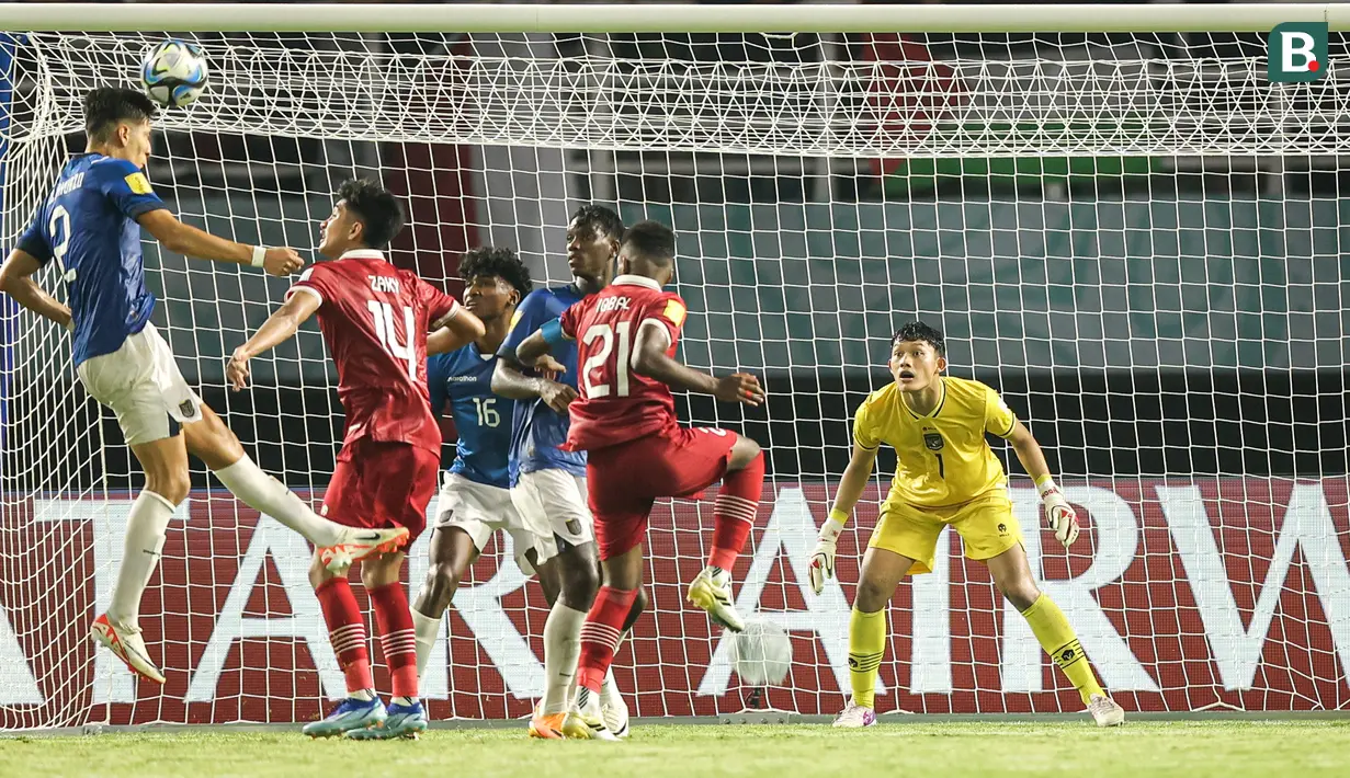 Kiper Timnas Indonesia U-17, Ikram Algiffari bersiap di bawah mistar gawang saat pemain Timnas Ekuador U-17, Jair Collahuazo (kiri) melepaskan sundulan pada laga pertama Grup A Piala Dunia U-17 2023 di Stadion Gelora Bung Tomo, Surabaya, Jumat (10/11/2023). (Bola.com/Bagaskara Lazuardi)