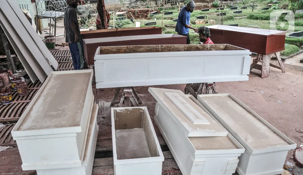 Pekerja menyelesaikan pembuatan peti jenazah di TPU Pondok Kelapa, Jakarta, Selasa (13/7/2021). Melonjaknya angka kematian Covid-19 di Ibu Kota beberapa hari terakhir, menyebabkan jumlah permintaan peti jenazah kembali meningkat hingga membuat pasokan bahan baku menipis (merdeka.com/Iqbal S Nugroho)