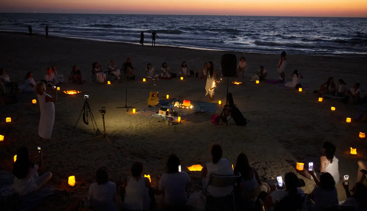 Wanita mengambil bagian dalam upacara Tashlich, di mana mereka menuliskan hal-hal yang ingin mereka lepaskan sebelum melemparkannya ke dalam api, di pantai di Tel Aviv, Israel (14/9/2021). (AP Photo/Maya Alleruzzo)
