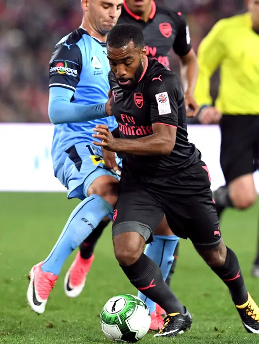 Alexandre Lacazette berusaha membawa bola dari kawalan pemain Sydney FC Christopher Zuvela pada pertandingan persahabatan di Sydney (13/7). Lacazette bermain sebagai pemain pengganti menggantikan Danny Welbeck di menit 68. (AFP Photo/William West)