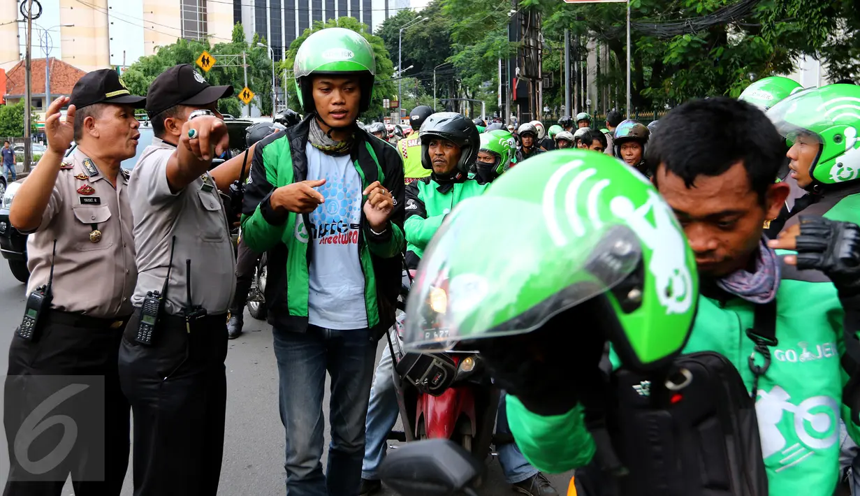 Petugas saat memberikan arahan kepada pengemudi Go-Jek yang diamankan di kawasan Senayan, Jakarta Pusat, Selasa (22/3). Mereka diamankan karena diduga akan melakukan aksi balasan terhadap Sopir Taksi.(Liputan6.com/Fery Pradolo)