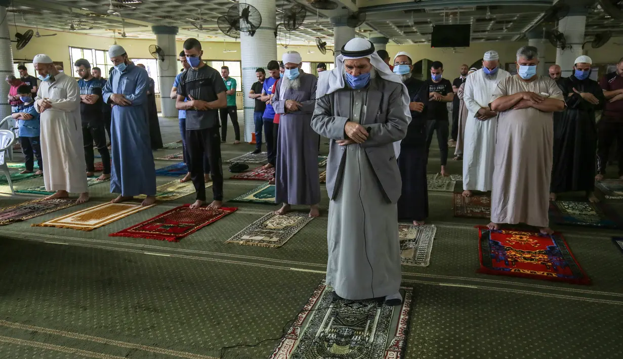 Para pria Palestina mengenakan masker saat ambil bagian dalam salat zuhur di masjid Al-Abrar di Rafah, selatan Jalur Gaza, Rabu (3/6/2020). Masjid-masjid kembali dibuka bagi jemaah menyusul pelonggaran pembatasan Covid-19 di Jalur Gaza. (Photo by SAID KHATIB / AFP)