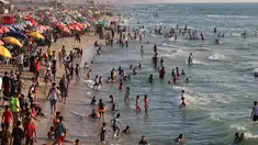 Warga Palestina berkumpul di pantai Beit Lahia di Jalur Gaza utara saat para siswa memulai liburan musim panas mereka pada 3 Juni 2022. Sejumlah warga menikmati musim panas dengan berenang dan bermain air di pantai. (MOHAMMED ABED / AFP)