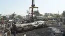 Alat berat saat akan mengevakuasi salah satu gerbong kereta tangki minyak di lokasi kecelakaan di Distrik Sheikhupura, Punjab, Selasa (28/3). Akibat kejadian tersebut sejumlah gerbong kereta dan kendaraan hangus terbakar. (AFP Photo / Ludovic Marin)