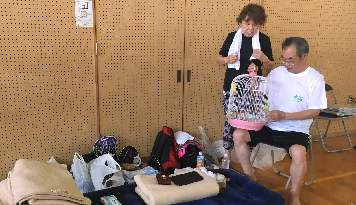 Pengungsi Akira Tanimoto bersama istrinya, Chieko Tanimoto memeriksa burung peliharaannya di pusat evakuasi di Hiroshima, Jepang, Selasa (10/7). Pemerintah Jepang menyatakan banjir disertai tanah longsor telah menewaskan 179 orang. (AP Photo/Haruka Nuga)