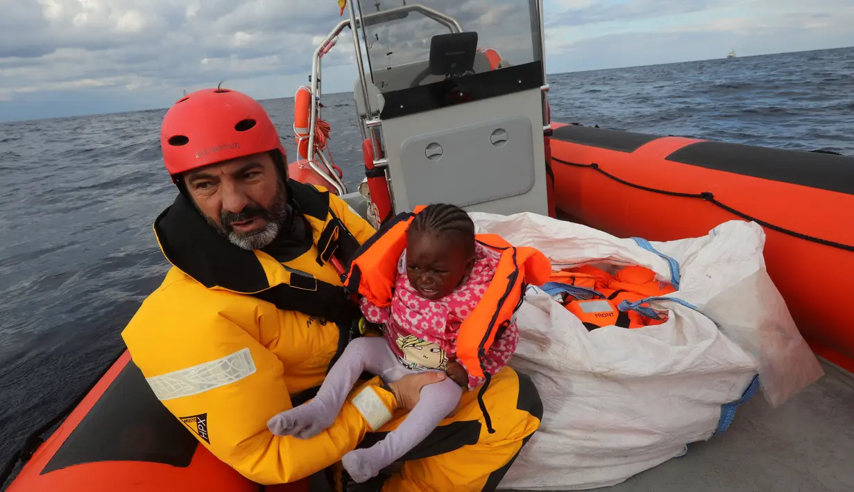 Oscar Camps, pendiri Spanyol LSM Proactiva Open Arms saat menyelamatkan seorang anak imigran di perahu yang penuh sesak di Laut Meditarania, sekitar 36 mil laut dari lepas pantai Libya (2/2). (Reuters/Yannis Behrakis)
