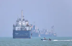 Sebuah perahu motor kecil melewati kapal-kapal yang berlabuh di Selat Hormuz di lepas pantai Bandar Abbas, Iran, Kamis, 11 Juni 2026. (Amirhosein Khorgooi/ISNA via AP)