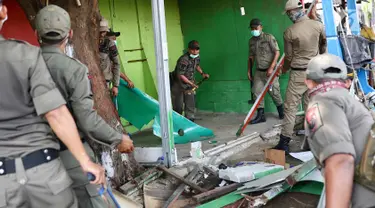 Petugas Satpol PP membongkar bangunan semi permanen di Jalan Nusantara Raya, Depok, Jawa Barat, Rabu (18/4). Pembongkaran dilakukan untuk menertibakan bangunan liar yang berdiri di sepanjang trotoar. (Liputan6.com/Immanuel Antonius)