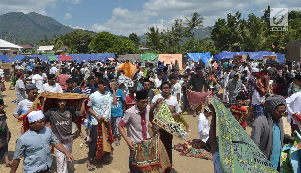 Umat muslim usai melaksanakan salat Jumat di sebuah ladang di dekat tempat penampungan sementara setelah gempa di Pemenang, Lombok (10/8). Jumlah Korban tewas akibat gempa dahsyat 6,9 SR di pulau Lombok melonjak di atas 300 orang. (AFP Photo/Adek Berry)