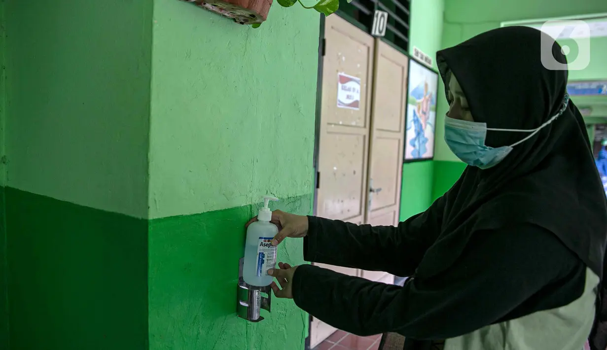 Seorang guru memakai sanitizer di SDN Kenari 08, Jakarta, Selasa (6/4/2021). Uji coba pembelajaran tatap muka terbatas di DKI Jakarta akan dilakukan dengan menerapkan protokol kesehatan COVID-19 yang ketat. (Liputan6.com/Faizal Fanani)