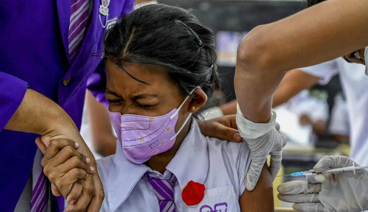 Seorang gadis sekolah bereaksi ketika seorang petugas kesehatan menyuntiknya dengan dosis vaksin Pfizer-BioNTech terhadap virus corona Covid-19 untuk kelompok usia 12-15 tahun di sebuah lembaga pendidikan di Kolombo, Sri Lanka (7/1/2022). (AFP/Ishara S. Kodikara)