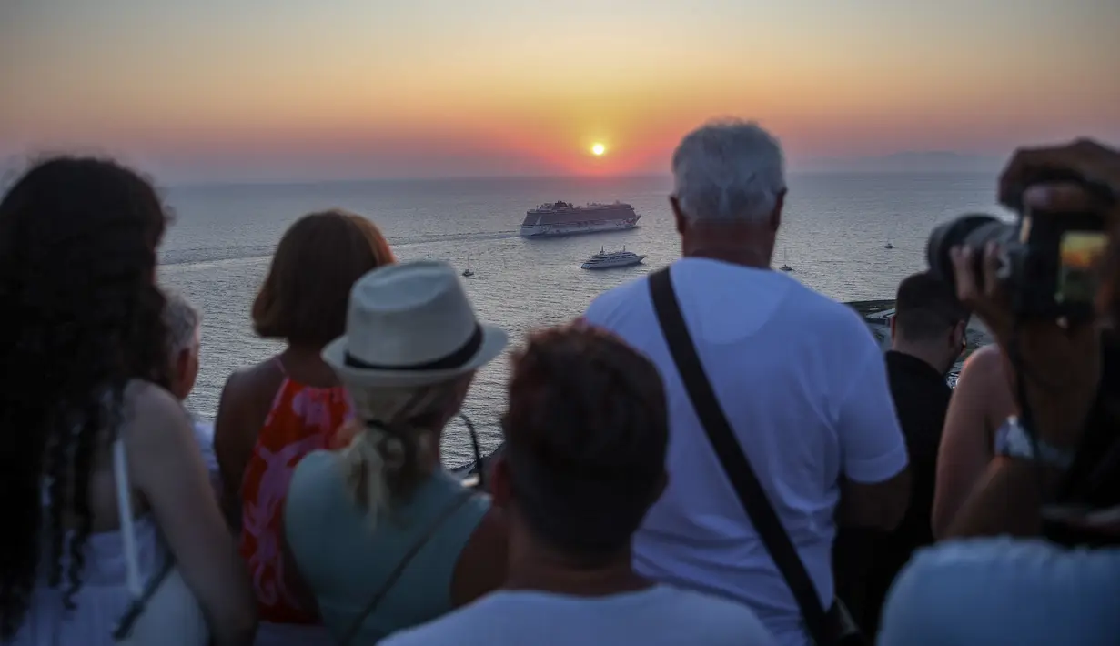 Salah satu gambar paling abadi dari merek wisata musim panas Yunani adalah matahari terbenam yang terkenal di dunia di Pulau Santorini, dibingkai oleh kubah gereja berwarna biru laut di tebing bergerigi yang tinggi di atas kaldera gunung berapi. (Aris Oikonomou / AFP)