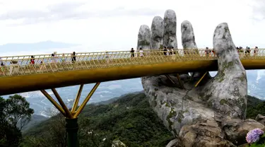 Pengunjung berjalan di sepanjang Golden Bridge di Perbukitan Ba Na dekat Danang, Vietnam, Selasa (31/7). Golden Bridge juga disebut-sebut sebagai Jembatan Tangan Tuhan karena ada dua tangan raksasa yang menopangnya. (Linh PHAM/AFP)