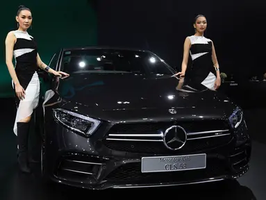 Dua model berpose di samping Mercedes Benz CLS 53 2019 selama Thailand International Motor Expo di Bangkok (29/11). Thailand International Motor Expo bertema “Enjoy Driving! Before Driverless Era”.  (AFP Photo/Lillian Suwanrumpha)
